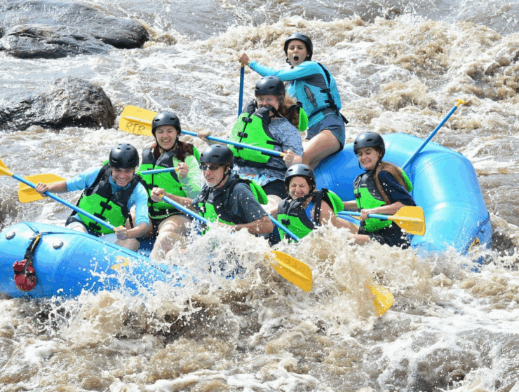 Happy family with children rafting on Big Thompson River near Estes Park, Colorado - gentle rapids, safety gear, and mountain views